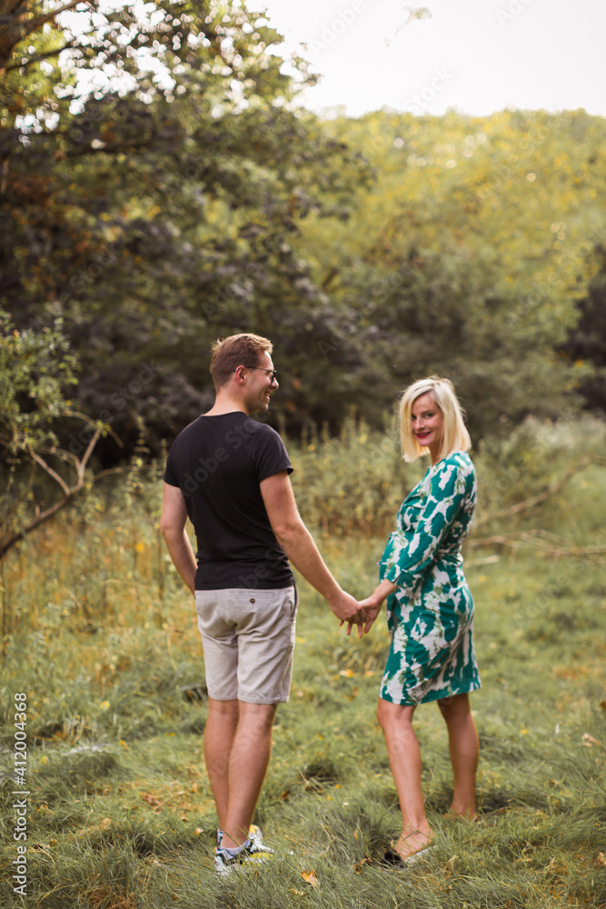 The happy pregnant couple is walking in the garden The happy pregnant couple is walking in the garden