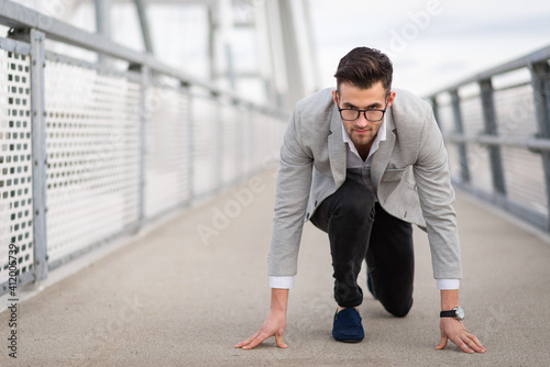 Businessman ready to run on the bridge. Focused yuppie ready to start with copy space