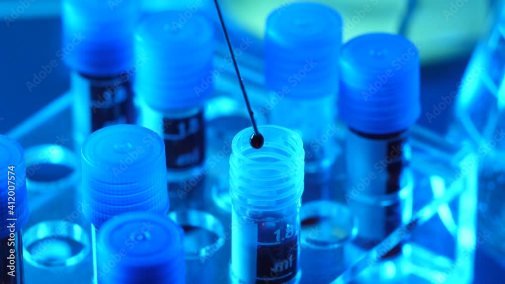 In a laboratory, a syringe is dropping droplets of blood into a test tube In a laboratory, a syringe is dropping droplets of blood into a test tube