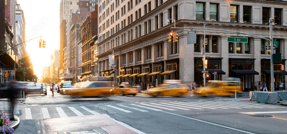 Yellow taxis driving through the busy intersection of 5th Avenue and 23rd Street in Manhattan, New York City