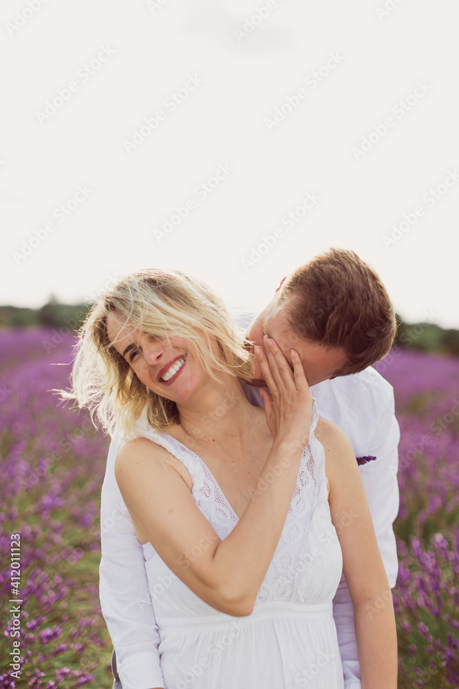 The young man kissing his smiling pregnant wife in the lavender field The young man kissing his smiling pregnant wife in the lavender field