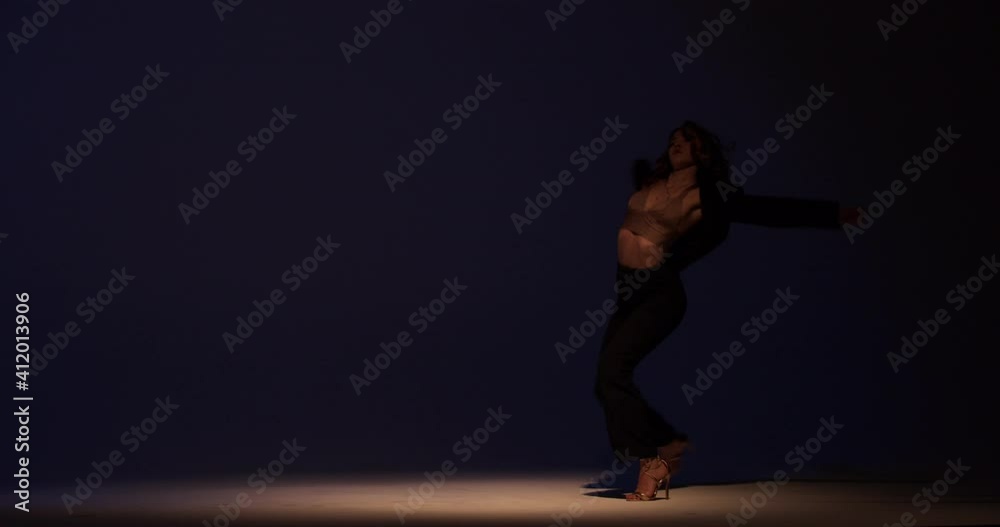 Sexy dancer is performing in the studio, dancing under the spotlight, 4k