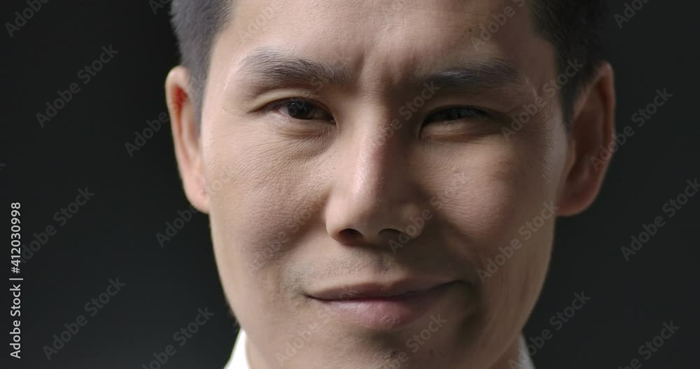 Portrait and close up shot of young handsome asian businessman looking to camera with attractive smile. People and business concept. Slow Motion. Portrait and close up shot of young handsome asian businessman looking to camera with attractive smile. People and business concept. Slow Motion.