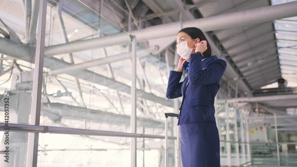 Caucasian flight attendant put on face mask, walking in the airport. Caucasian flight attendant put on face mask, walking in the airport.