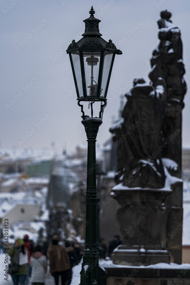 snow covered street lights  and statues on old stones Charles Bridge on the Vltava River in winter in the center of the town and on the bridge on the sidewalk 
