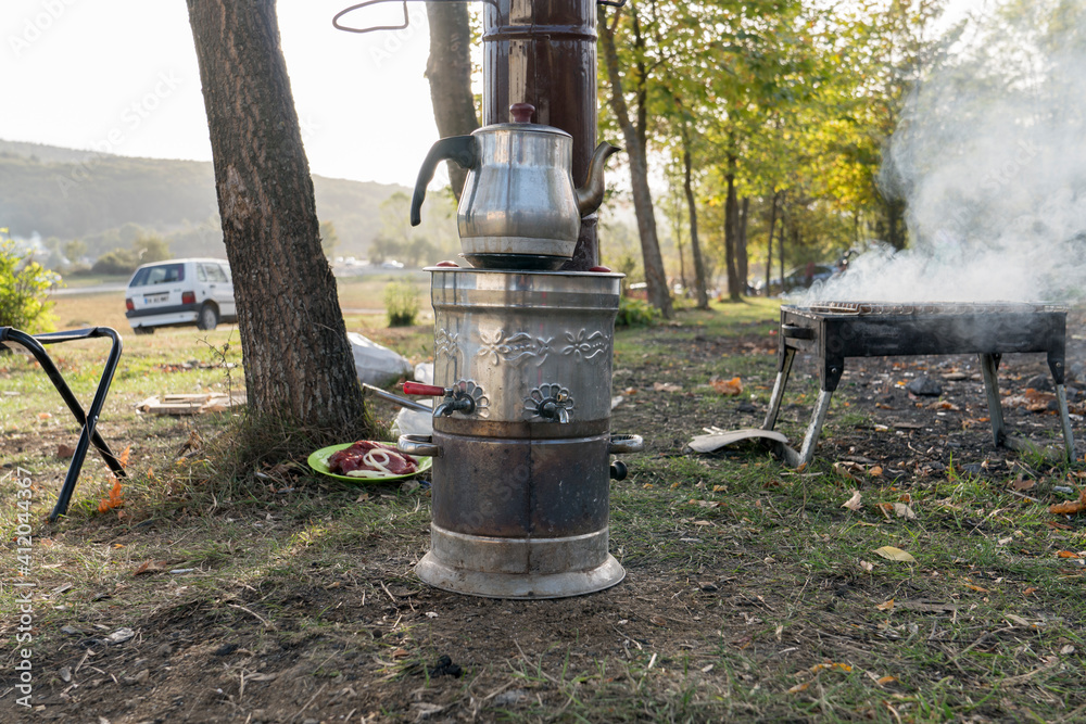 samovar and an aluminium tea pot on it on the ground in countryside samovar and an aluminium tea pot on it on the ground in countryside