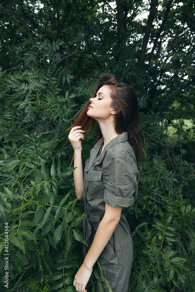 woman in forest touches head hair and landscape green jumpsuit travel woman in forest touches head hair and landscape green jumpsuit travel