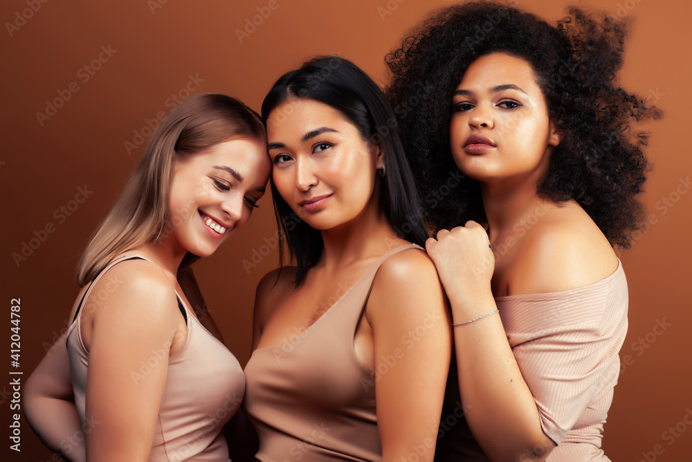 young pretty asian, caucasian, afro woman posing cheerful together on brown background, lifestyle diverse nationality people concept