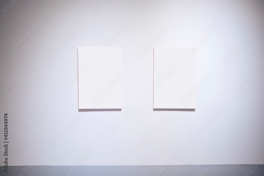 Two blank space white frame canvas on white wall. Art work gallery. Two blank space white frame canvas on white wall. Art work gallery.