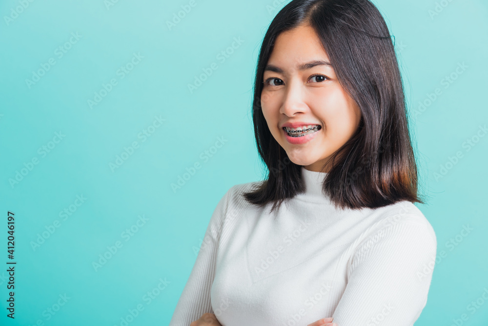 Young beautiful Asian woman smiling with crossed arms, Portrait of positive confident female stand cross one's arm, studio shot isolated on a blue background Young beautiful Asian woman smiling with crossed arms, Portrait of positive confident female stand cross one's arm, studio shot isolated on a blue background