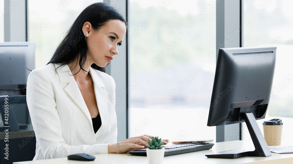 Businesswoman sitting at desk and working alone in office. Businesswoman sitting at desk and working alone in office.