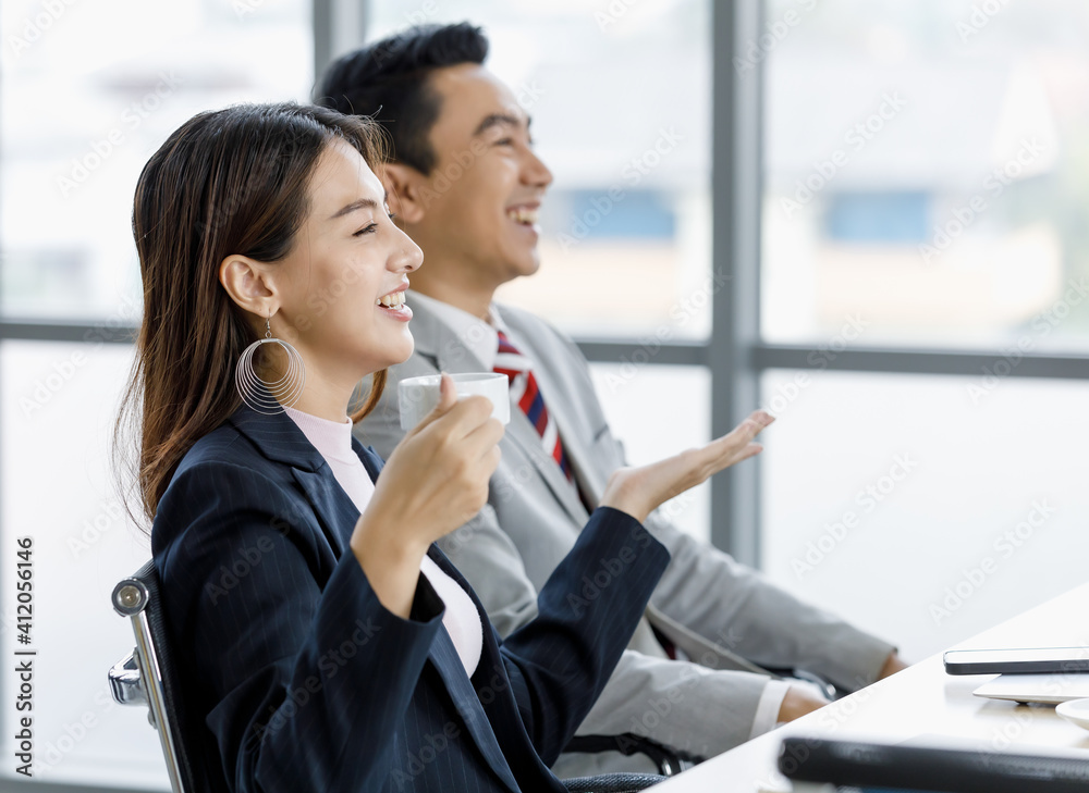 Businesspeople Asian man ans woman sitting and talking together in office and drinking coffee at a break time. Businesspeople Asian man ans woman sitting and talking together in office and drinking coffee at a break time.