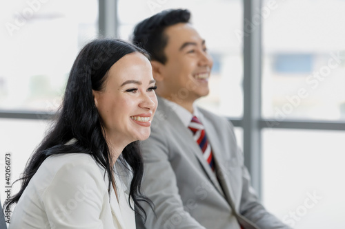 Caucasian businesswoman and Asian businessman talking together in office with funny and happy.