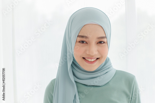 Portrait of 30s beautiful Muslim girl wearing hijab traditional religious cloth looking to camera with a lovely smile on white background © Bangkok Click Studio