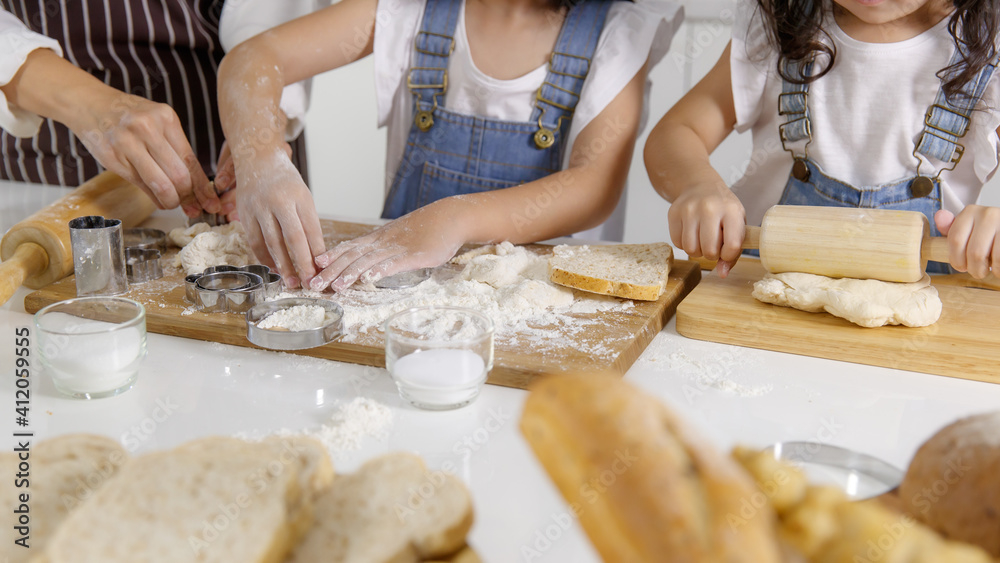 Hands of woman adult and little girls mixing flour on board to make bakery
