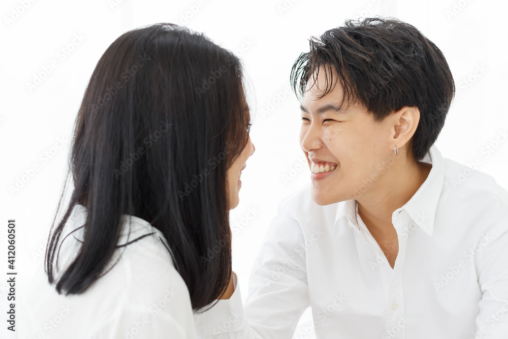 LGBTQ couple lovers, a handsome girl as man or butch and femme, spending and sharing loving time in white bedroom with fun, warmth, and happiness LGBTQ couple lovers, a handsome girl as man or butch and femme, spending and sharing loving time in white bedroom with fun, warmth, and happiness