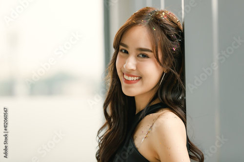 Portrait of young and beautiful Asian woman with pieces of confetti paper on her hairs after celebrating party. Taken with natural light