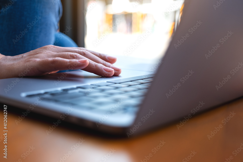 Closeup image of a woman working and touching on laptop touchpad on wooden table - obrazy, fototapety, plakaty 