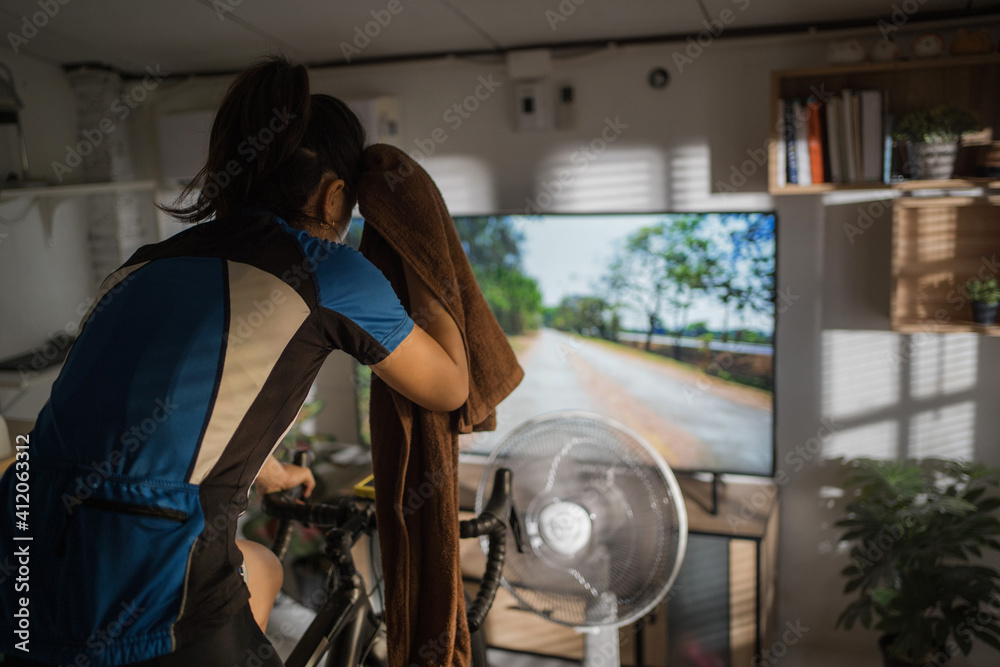 Asian woman cyclist. She is exercising at home. She is playing games in the virtual world.