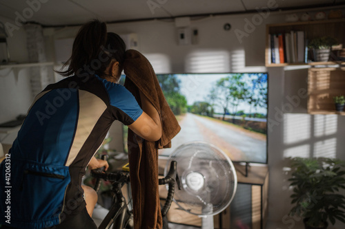 Asian woman cyclist. She is exercising at home. She is playing games in the virtual world.