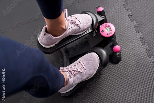 Obraz na płótnie Fitness girl training at home using a black and pink stepper machine