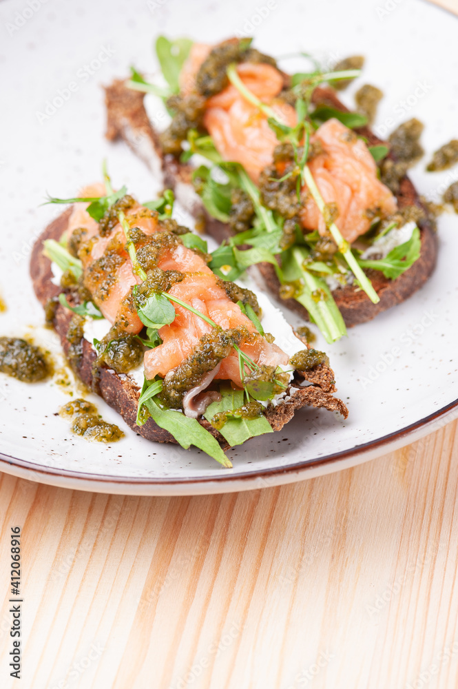 Salmon bruschetta with pesto in white plate Salmon bruschetta with pesto in white plate