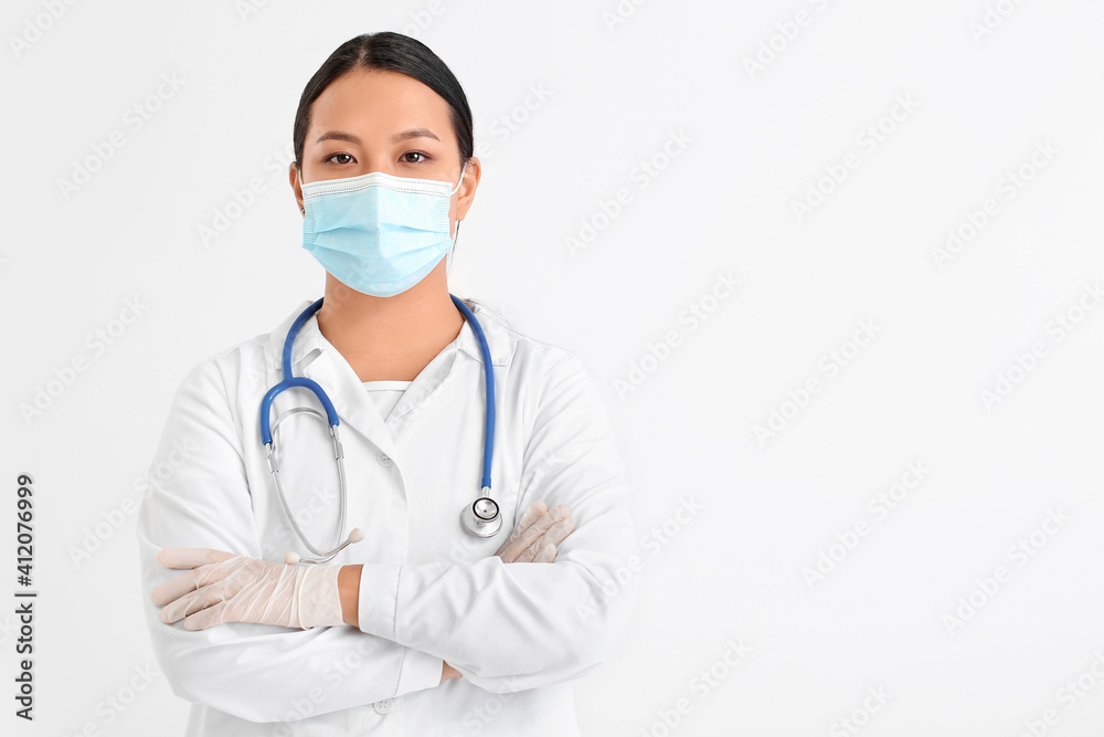 Portrait of female Asian doctor in medical mask on light background Portrait of female Asian doctor in medical mask on light background