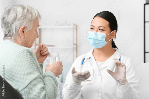 Doctor giving remedy to senior woman at home