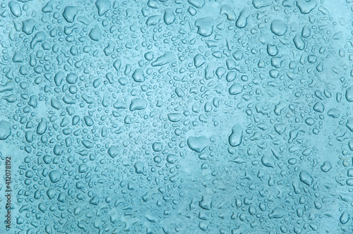 small and large drops of condensation on frosted colored glass