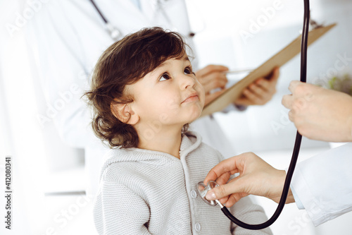 Woman-doctor examining a child patient by stethoscope. Cute arab toddler at physician appointment. Medicine concept