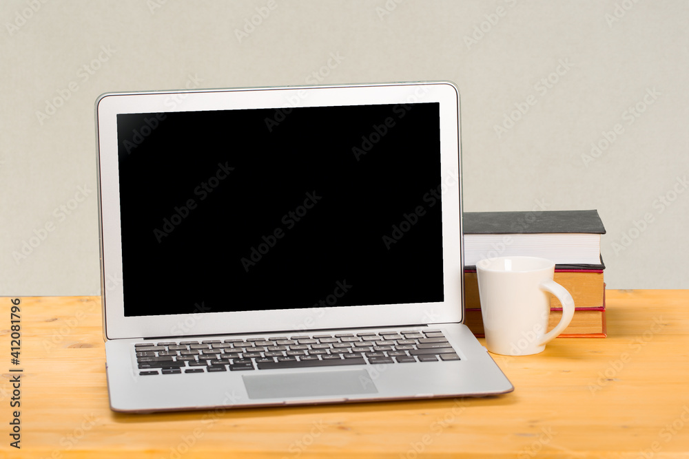Fototapeta premium Laptop with blank screen, cup of coffee and books or notebooks on a wooden table. mockup for your text. work from home