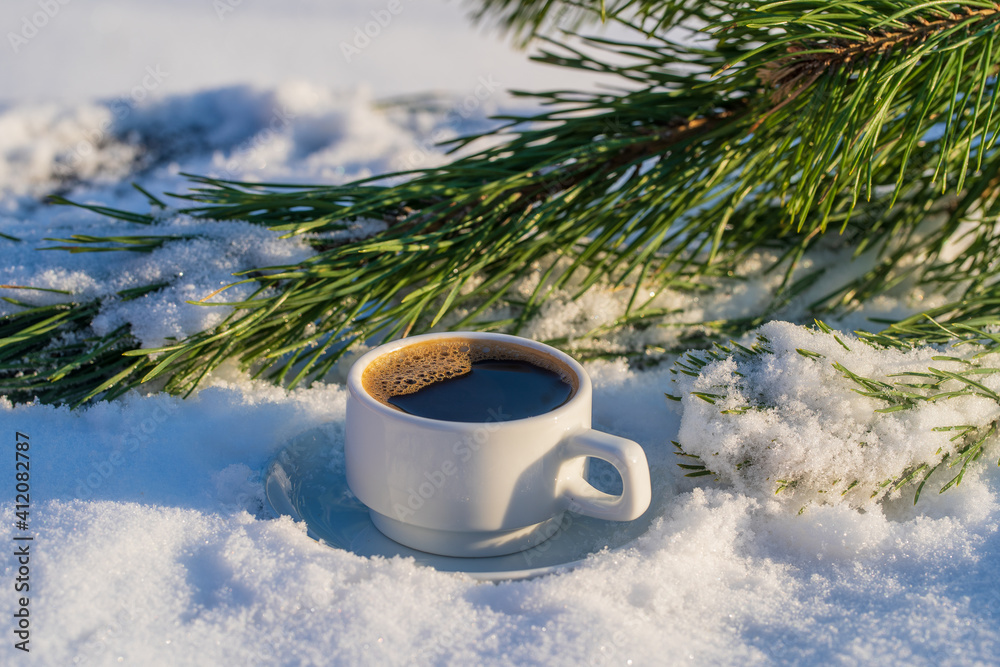 White cup of hot coffee on a bed of snow and white background, close up White cup of hot coffee on a bed of snow and white background, close up