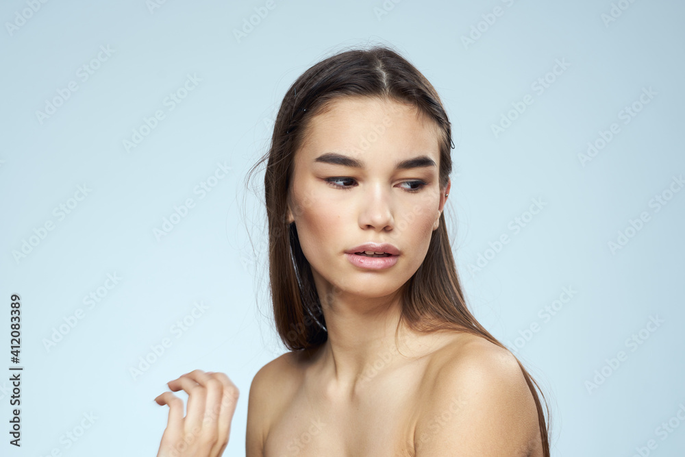 Pretty brunette with bared shoulders long hair body care blue background