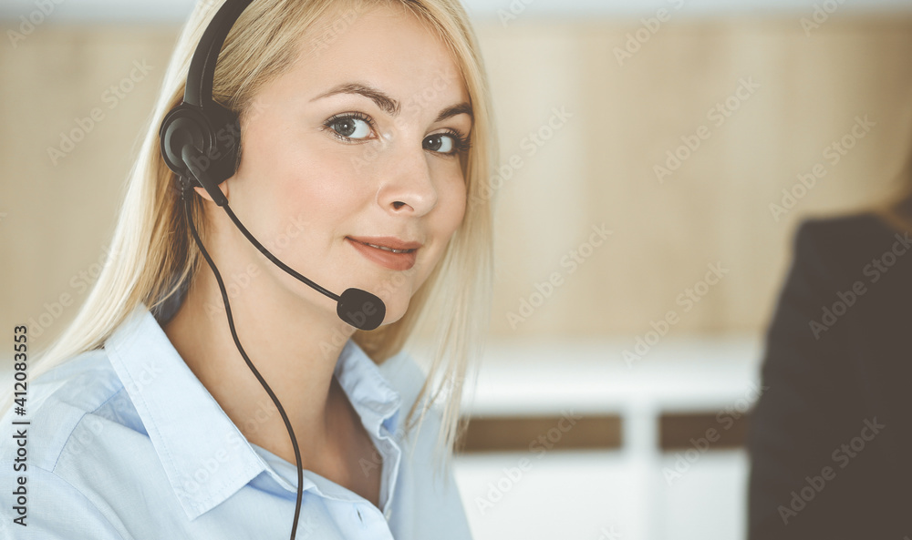 Blonde business woman sitting and communicated by headset in call center office. Concept of telesales business Blonde business woman sitting and communicated by headset in call center office. Concept of telesales business