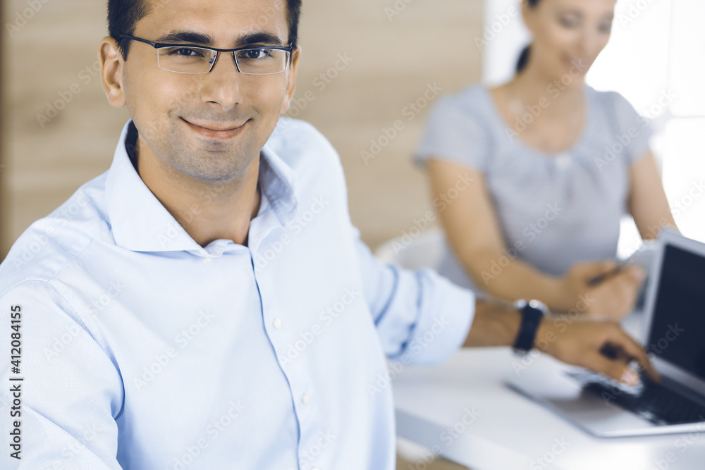 Businessman and business woman discussing questions while using a computer in modern office. Portrait of male entrepreneur at meeting. Group of diverse people Businessman and business woman discussing questions while using a computer in modern office. Portrait of male entrepreneur at meeting. Group of diverse people