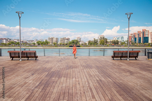 A girl in a dress walks on the promenade of Antalya © zhukovvvlad