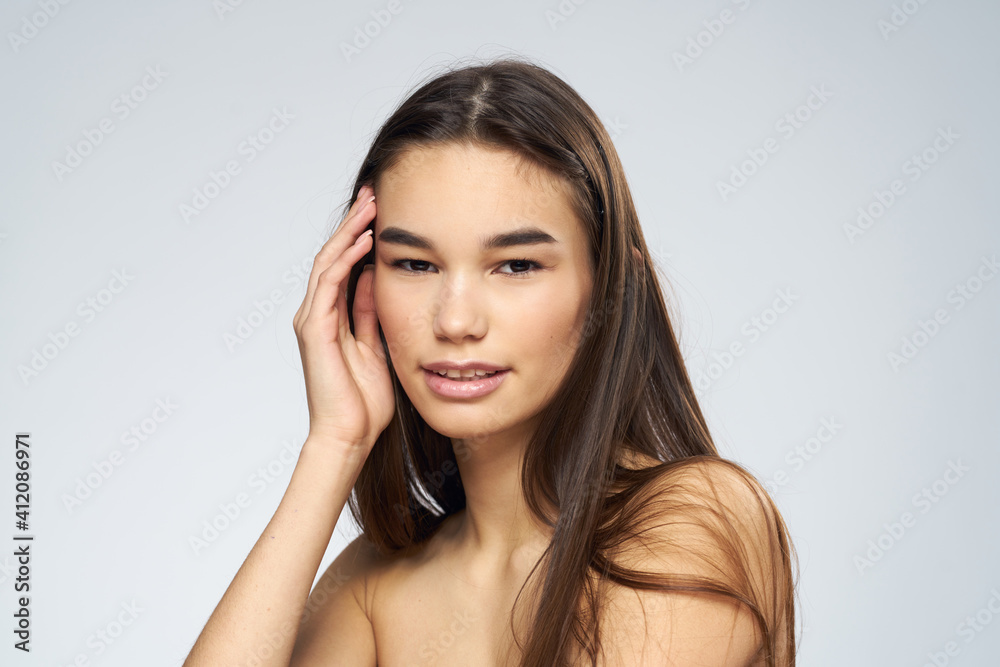 Pretty brunette naked shoulders long hair close-up light background Pretty brunette naked shoulders long hair close-up light background