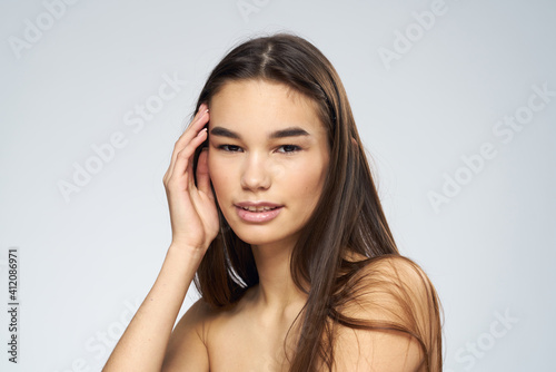 Pretty brunette naked shoulders long hair close-up light background