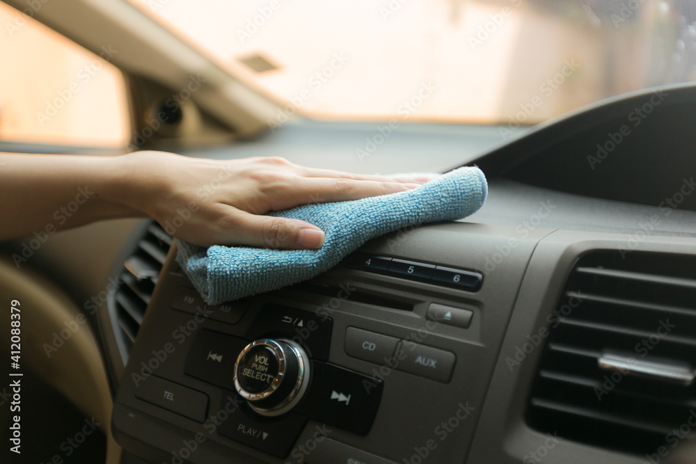 Close up worker hand cleaning console with microfiber cloth blue.