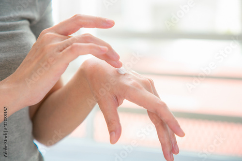 Close up of hands woman applying hand cream at home.