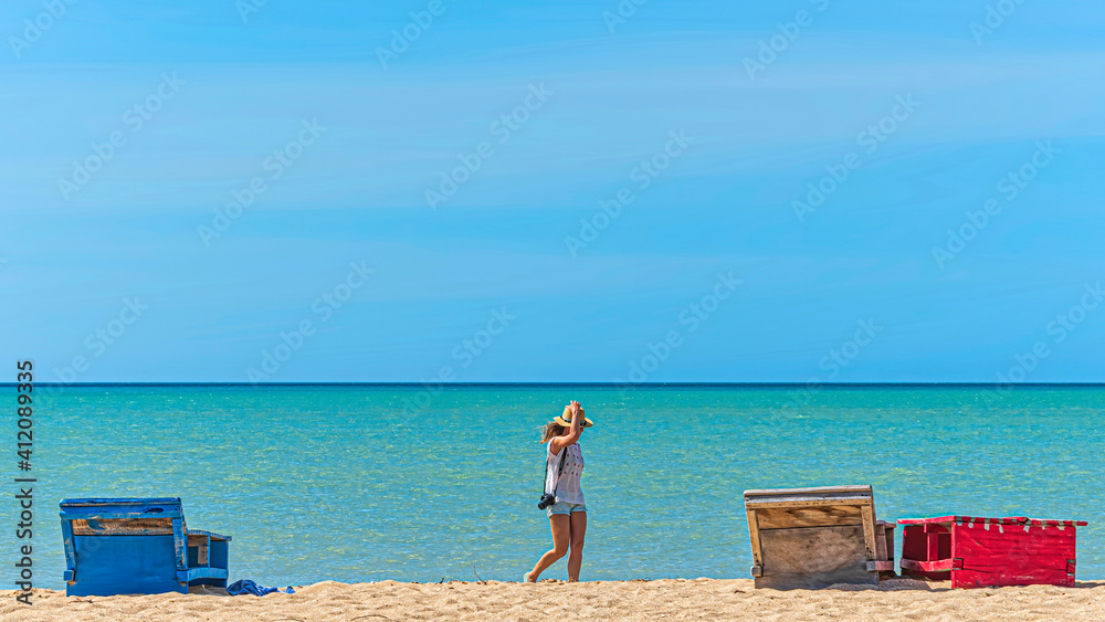 Girl walking on a tropical beach under a bright sun