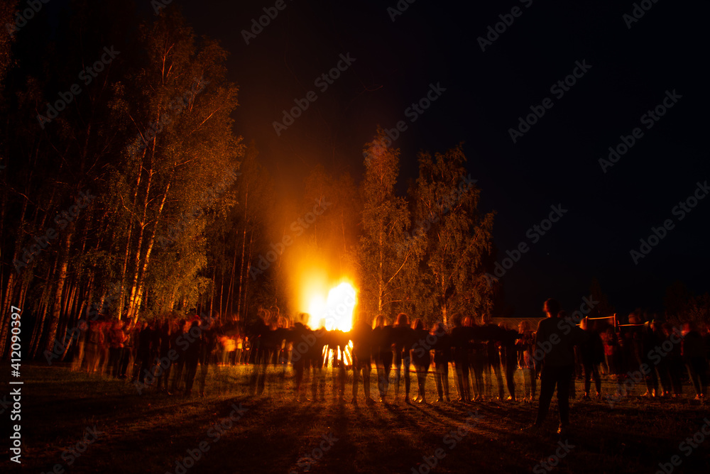 People standing around a big fire at night
