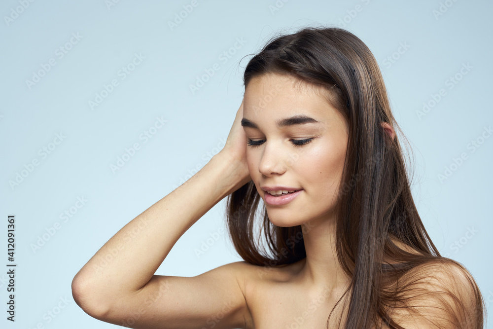 Pretty brunette with bared shoulders long hair body care blue background Pretty brunette with bared shoulders long hair body care blue background
