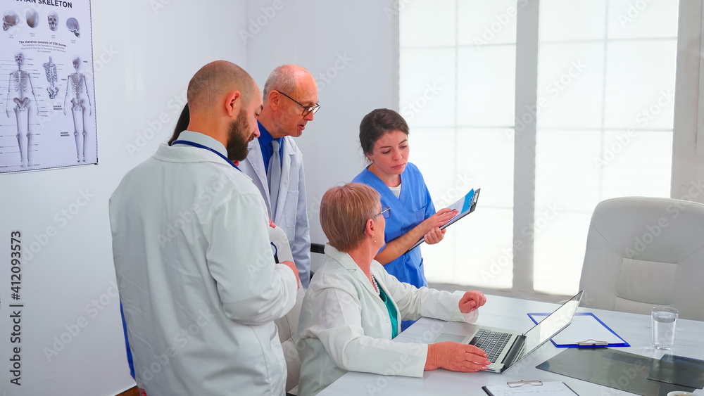 Obraz premium Medical team having a discussion about patient diagnosis looking at laptop screen in conference room. Clinic expert therapist discussing diagnosis about patients treatment issues record in workplace.