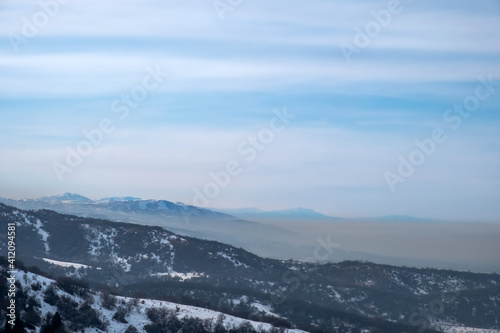 Mountains with smog rising from town. Visible border of clean and dirty air. Air pollution concept. © Adil