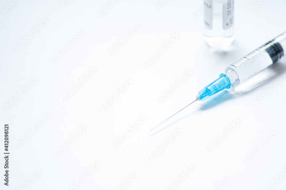 Syringe with needle without cover or top, vial or phial on a white empty space background ready to be used. Covid or Coronavirus vaccine or monoclonal antibodies background, close up Syringe with needle without cover or top, vial or phial on a white empty space background ready to be used. Covid or Coronavirus vaccine or monoclonal antibodies background, close up