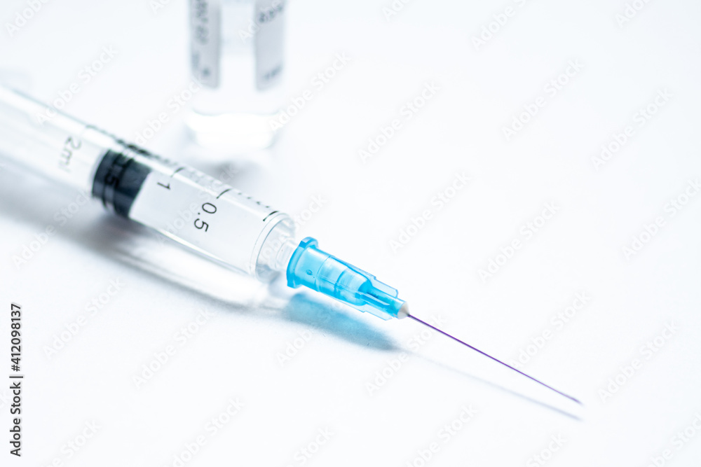 Syringe with needle without cover or top, vial or phial on a white empty space background ready to be used. Covid or Coronavirus vaccine or monoclonal antibodies background, close up Syringe with needle without cover or top, vial or phial on a white empty space background ready to be used. Covid or Coronavirus vaccine or monoclonal antibodies background, close up