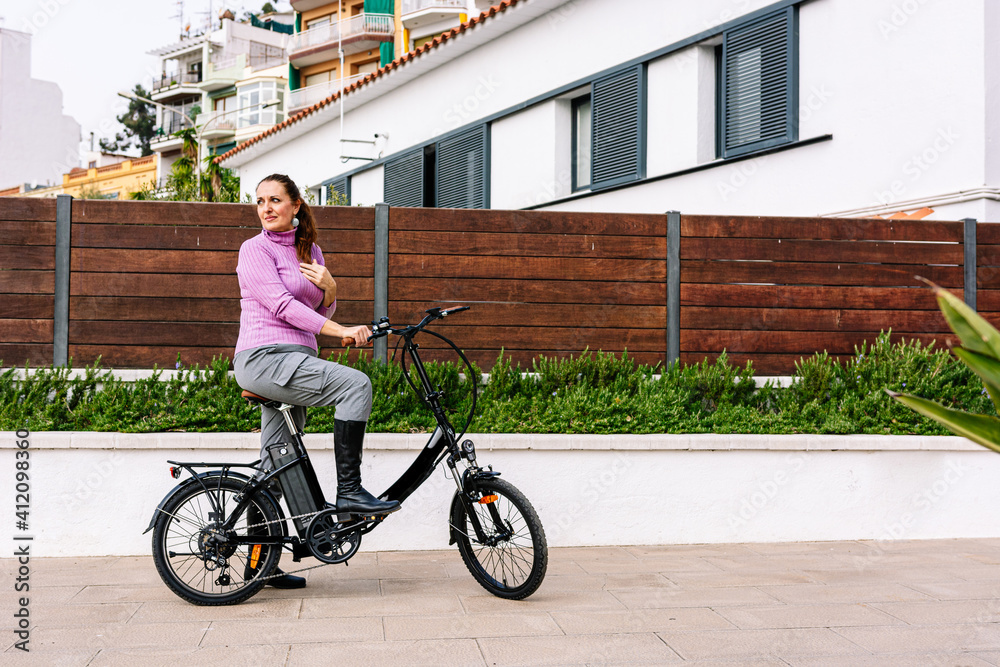 40-year-old woman riding her electric bicycle through the streets of the city 40-year-old woman riding her electric bicycle through the streets of the city