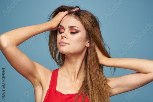Woman with wavy hair attractive look Red tank top blue background