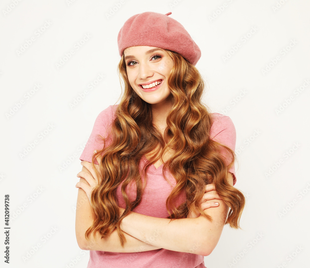 Happiness for everyone. Smiling blonde looks at the camera. Young woman with curly hair wearing a pink T-shirt and beret. Happiness for everyone. Smiling blonde looks at the camera. Young woman with curly hair wearing a pink T-shirt and beret.